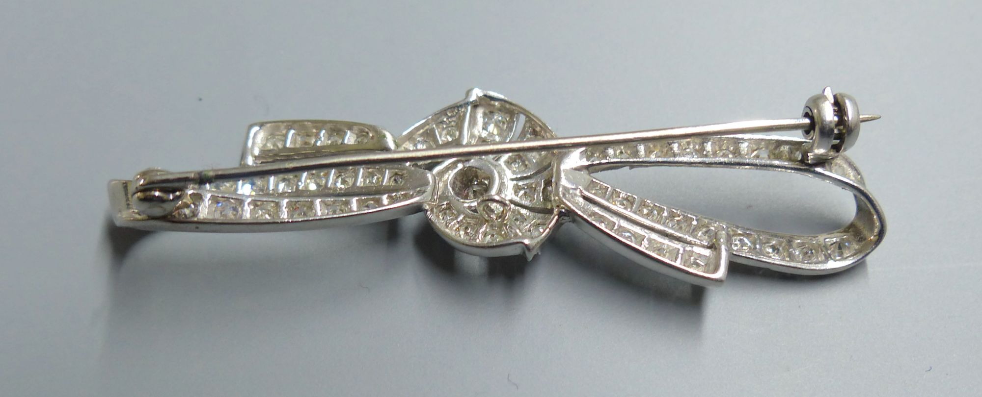 A white metal and millegrain set diamond cluster ribbon bow brooch, 54mm, gross 5.9 grams.